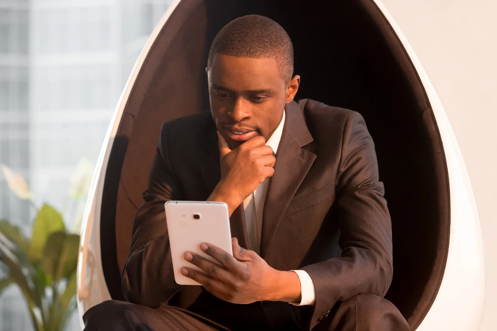 Un dirigeant en costume lit sur une tablette, absorbe par sa lecture
